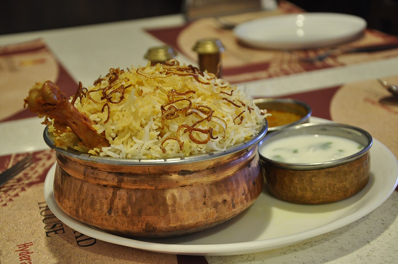 Hyderabadi chicken biryani served in a copper handi with raita
